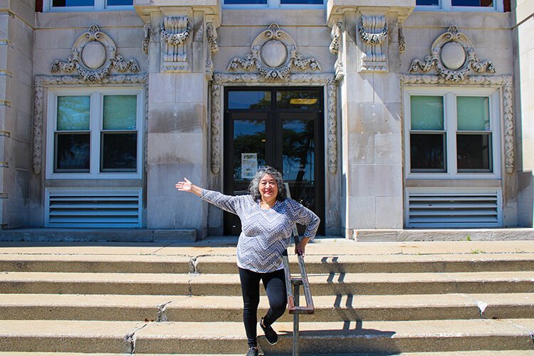 Irene Michels stands for a photograph, with the Main Building of St. Clair County Community College, a structure her late father contributed to during its construction.
