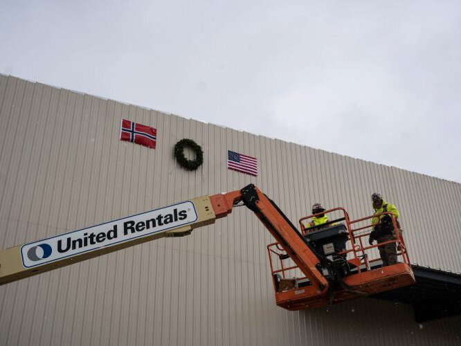 Workers place a wreath at the top of the plant as part of Kranselag.