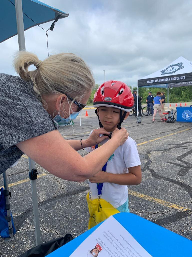 Fitting a child with a bicycle helmet, one of the projects of the Brain Injury Association of Michigan.