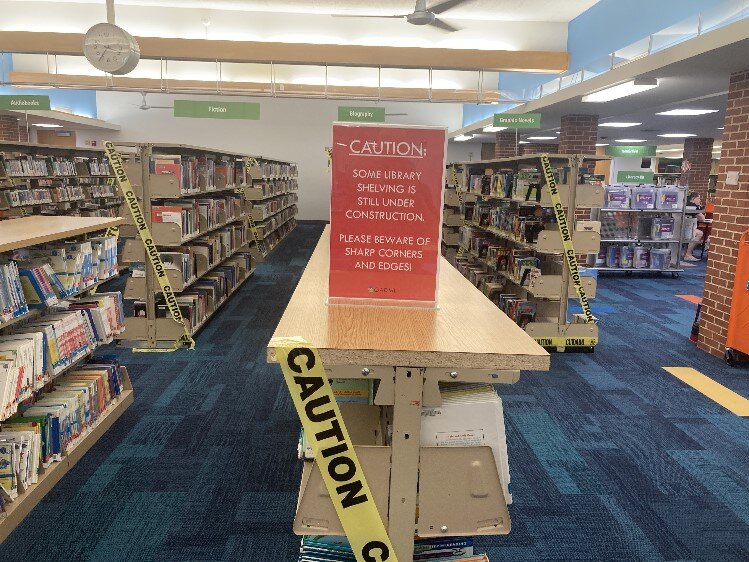 These shelves were “rescued” from floodwaters and were damaged, as signs and tape warn.  New shelving has been ordered but has not yet arrived.  