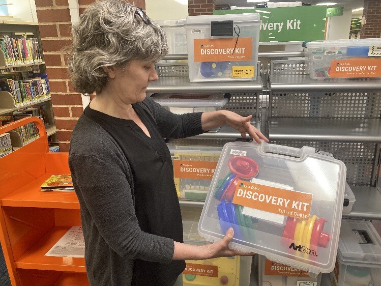  Kathy Brown shows off  “Tug of Boats,”  one of many Discovery Kits ready for check-out.  
