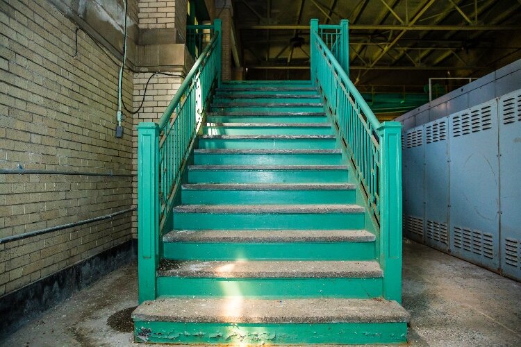 A staircase leads from the main entrance down to the main floor. The staircase is dusty, but sturdy.